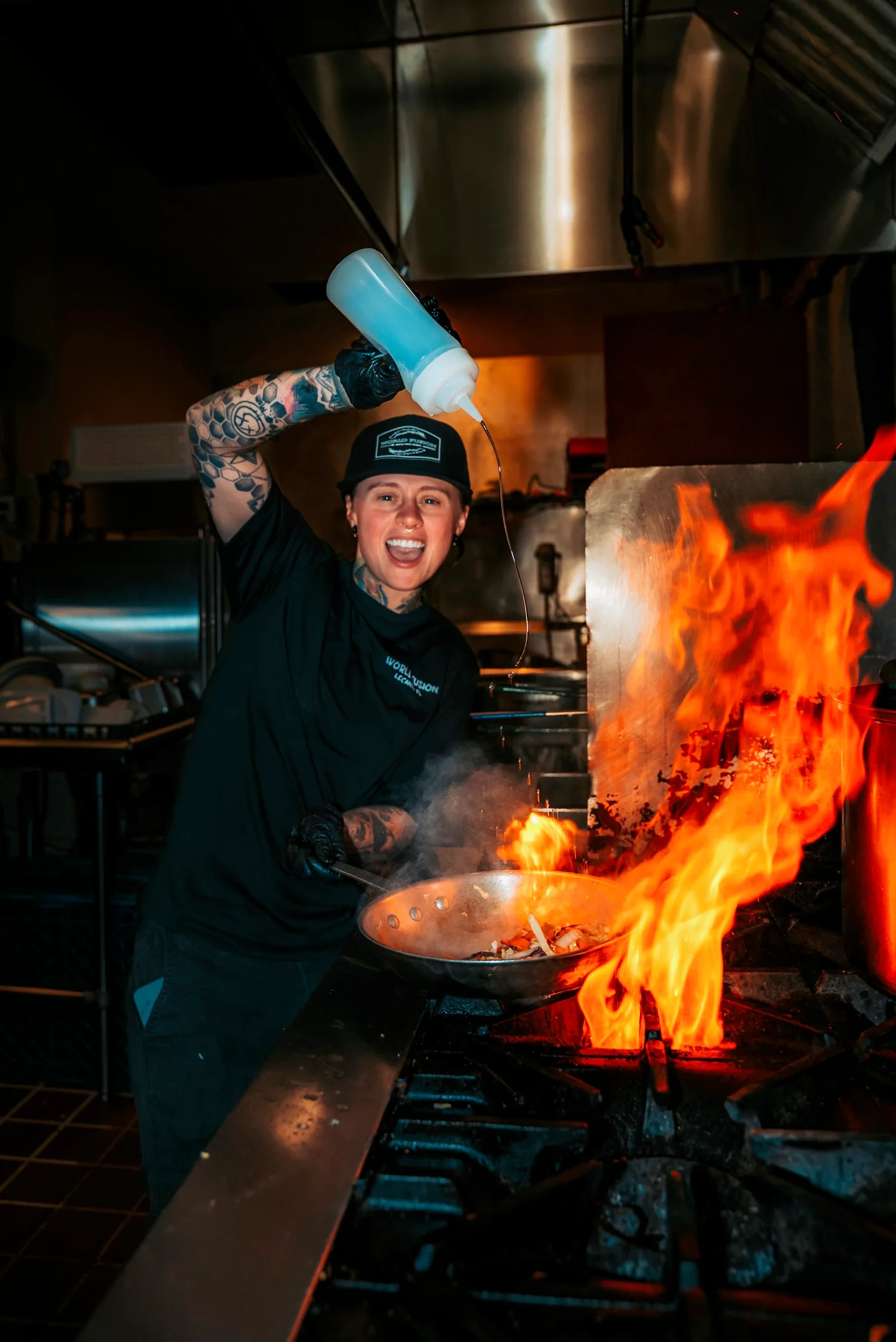 A World Fusion chef preparing a dish over an open flame in the kitchen